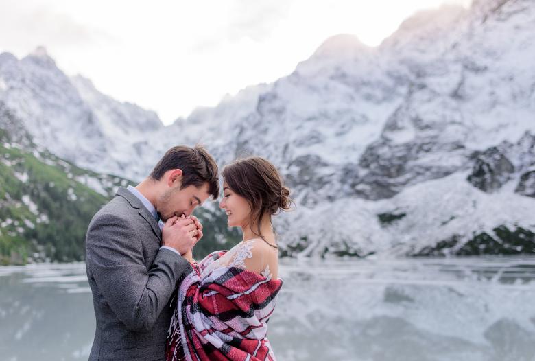 Couple kissing and hold hands in front of frozen lake 
