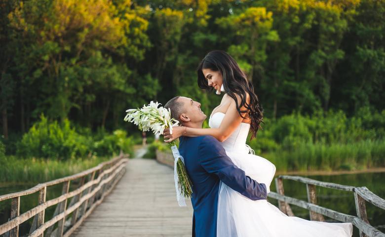groom lifting bride on wooden bridge