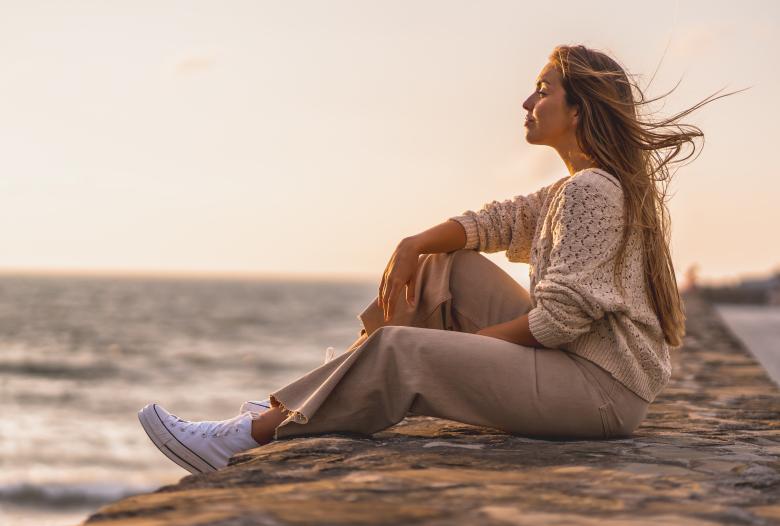 woman sitting on beach at sunset